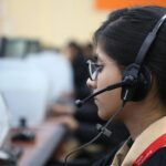 Side view of a woman working in a call center, wearing a headset and focused on her task.