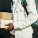 Close-up of a delivery person holding cardboard packages outdoors, showcasing modern urban logistics.